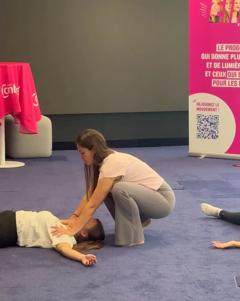 Coach Power Partners qui ajuste la posture d’une participante pendant le yoga Octobre Rose chez Nestlé Waters