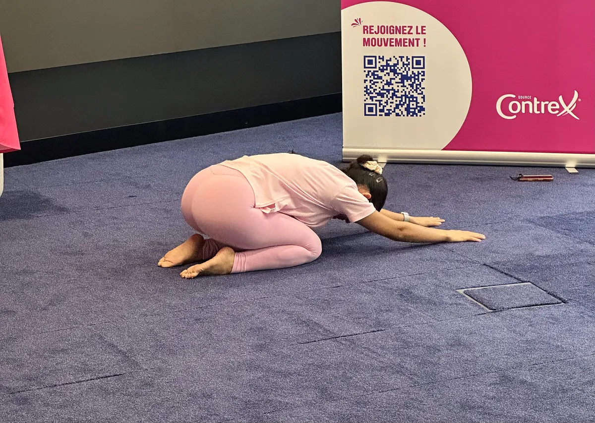 Posture de l'enfant pendant l'atelier yoga Octobre Rose, devant le kakémono Contrex